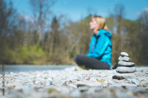 Meditation and relaxation: Cairn in the foreground, meditating woman in the blurry background. Enjoying the summer.