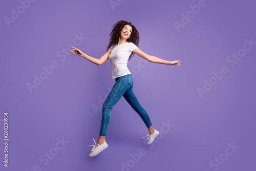 Full length side profile body size photo funky beautiful she her lady jump high spread hands arms shopping store mall wear casual jeans denim white t-shirt sneakers isolated purple violet background
