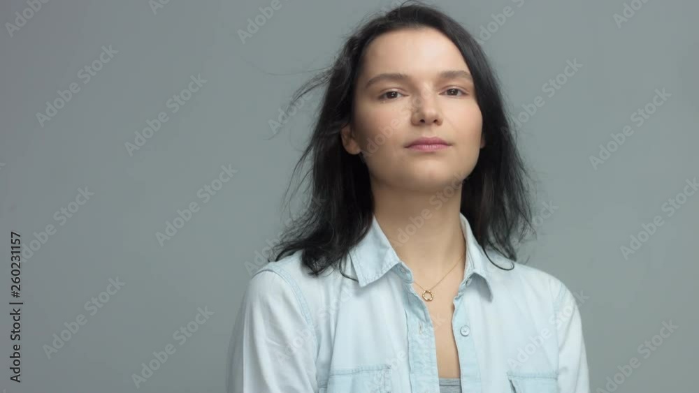 Brunette in studio portrait video shoot wwears jeans shirt with blowing hair slow motion from 60 fps Calm brunette portrait watching aside, touches her hair and then turns to the camera Brunette in studio portrait video shoot wwears jeans shirt with blowing hair slow motion from 60 fps Calm brunette portrait watching aside, touches her hair and then turns to the camera