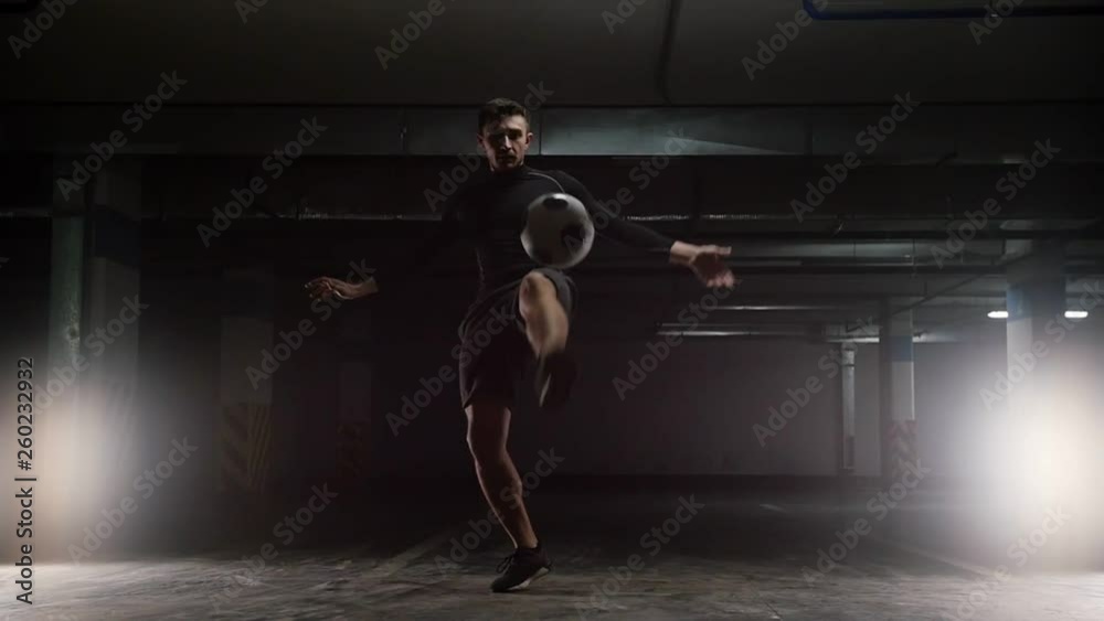 A young soccer man training tricks with the ball. Jumping above the ball