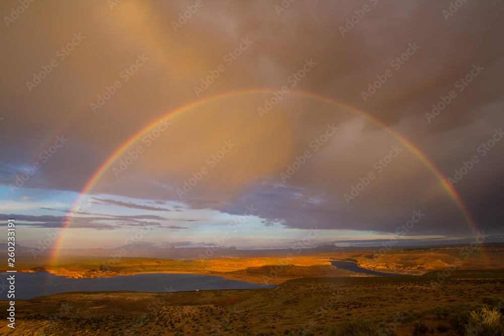 Double rainbow during rain in the desert of Arizona against the background of clouds and a river.