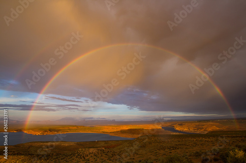 Double rainbow during rain in the desert of Arizona against the background of clouds and a river.