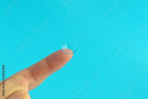 contact lens on finger on lblue background. photo