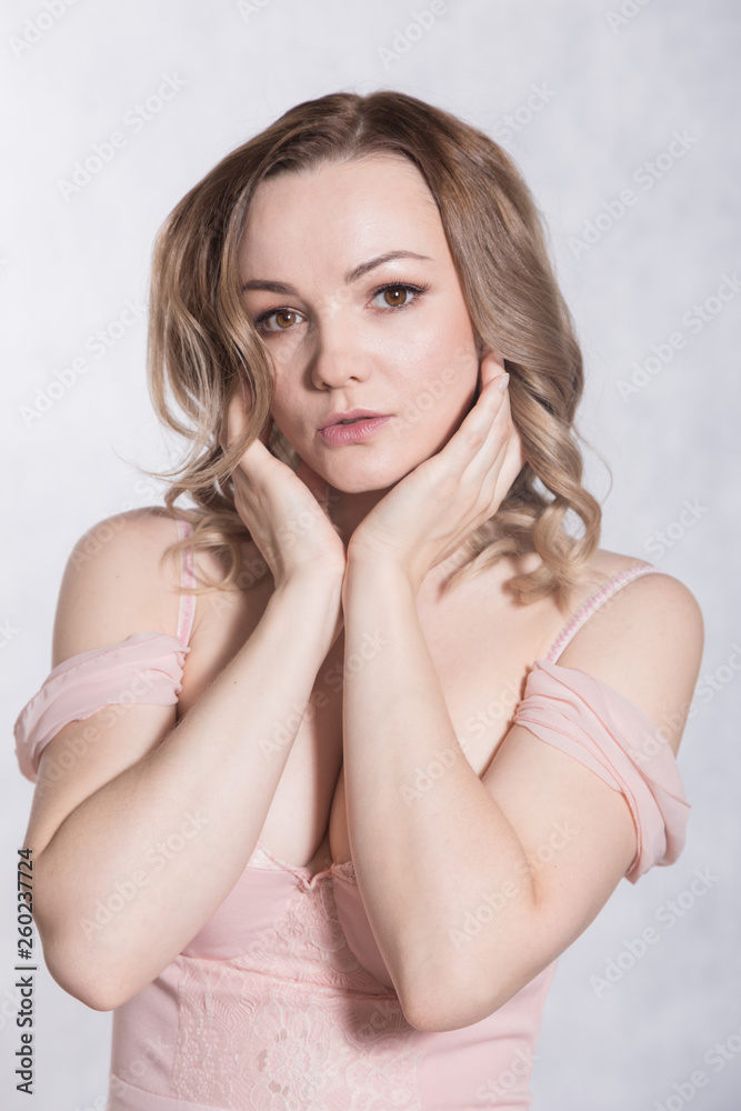 Portrait of beautiful young elegant female in pale pink wedding dress with big neckline, on a white background. Portrait of beautiful young elegant female in pale pink wedding dress with big neckline, on a white background.