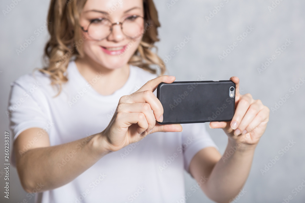 Beautiful young woman taking pictures on a smartphone.