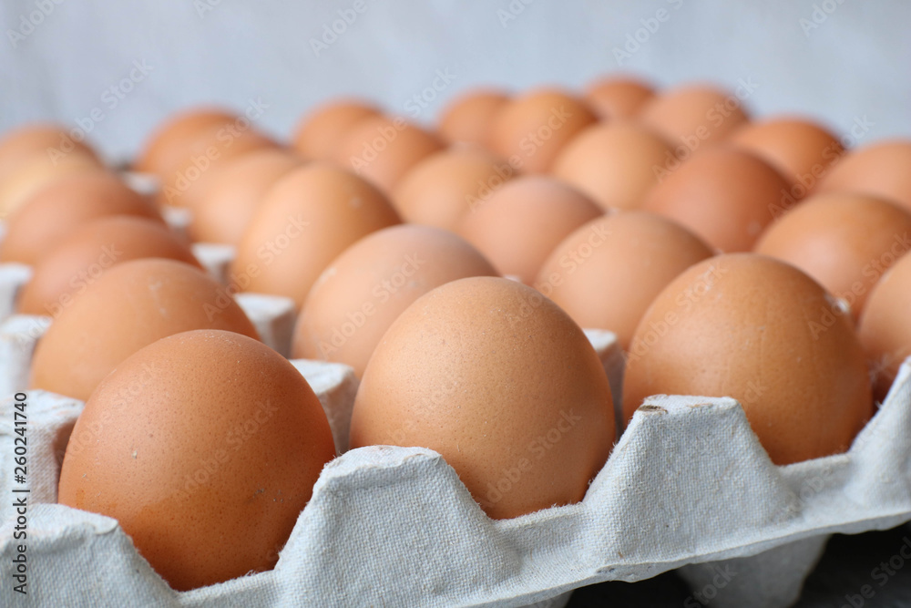 Carton with thirty fresh brown eggs on a grey concrete background. Side view Carton with thirty fresh brown eggs on a grey concrete background. Side view