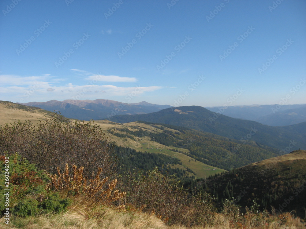 Mountain landscape with blue sky. View of the mountains and green hills from above.