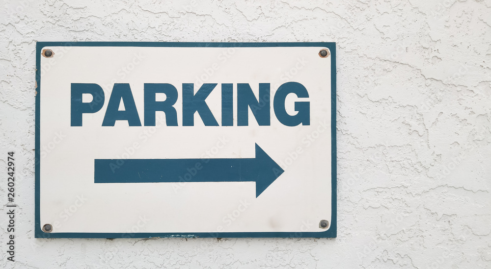 Parking sign on an exterior wall with direction arrow Parking sign on an exterior wall with direction arrow