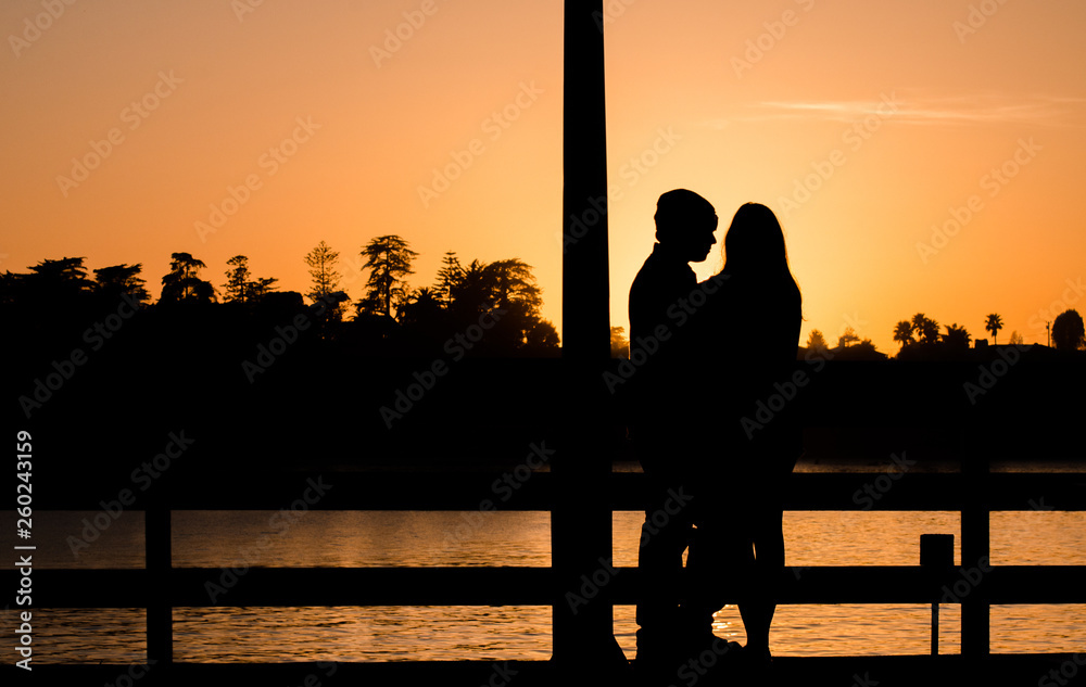 Romantic couple on a pier in Santa Cruz hugging during sunset