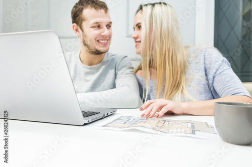 Lovely young couple, using a laptop and choosing a new apartment.