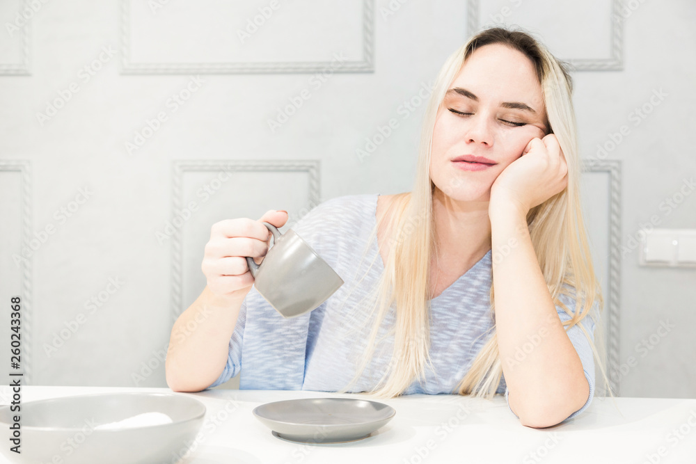 Young pretty woman falls asleep at breakfast in the kitchen. Young pretty woman falls asleep at breakfast in the kitchen.