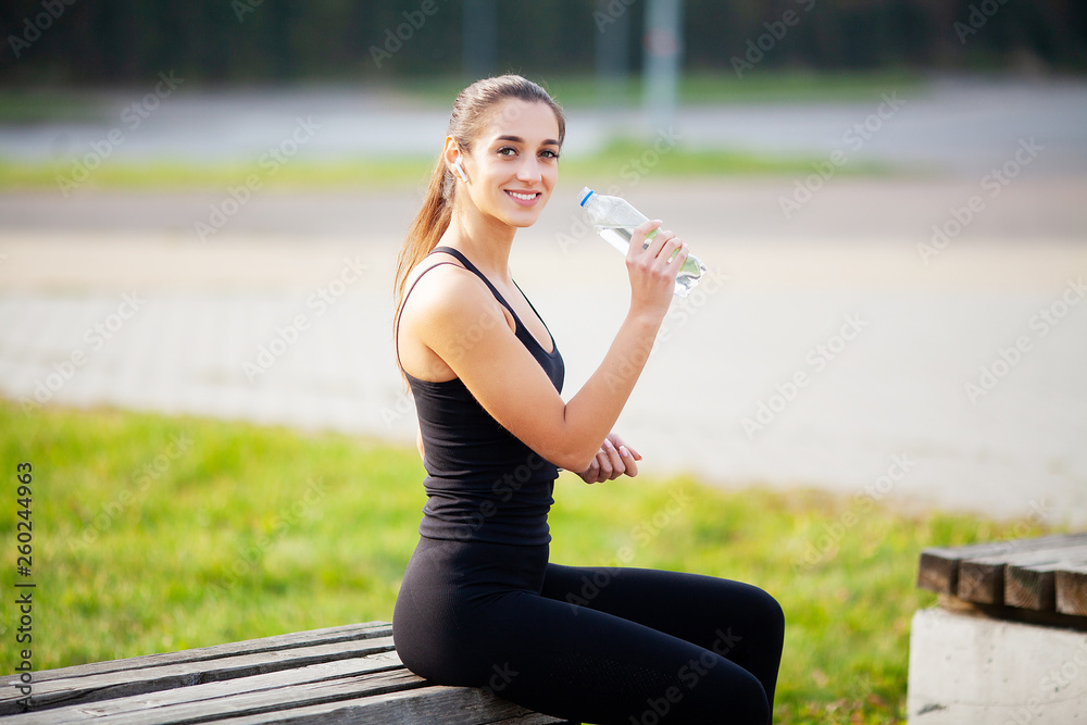 Fitness Girl. Young beautiful woman in sportswear drinking water in park Fitness Girl. Young beautiful woman in sportswear drinking water in park