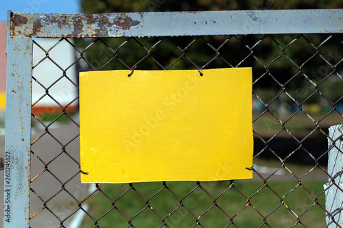 Φωτογραφία Closeup view of yellow empty blank sign with copyspace attached to metal fence outdoors