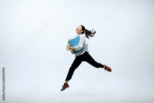 Getting faster and stronger. Happy woman working at office, jumping and dancing in casual clothes or suit isolated on white studio background. Business, start-up, working open-space concept. photo