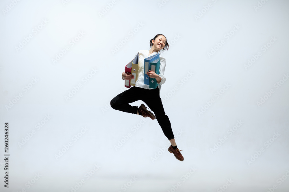 Winged by new deals. Happy woman working at office, jumping and dancing in casual clothes or suit isolated on white studio background. Business, start-up, working open-space concept.