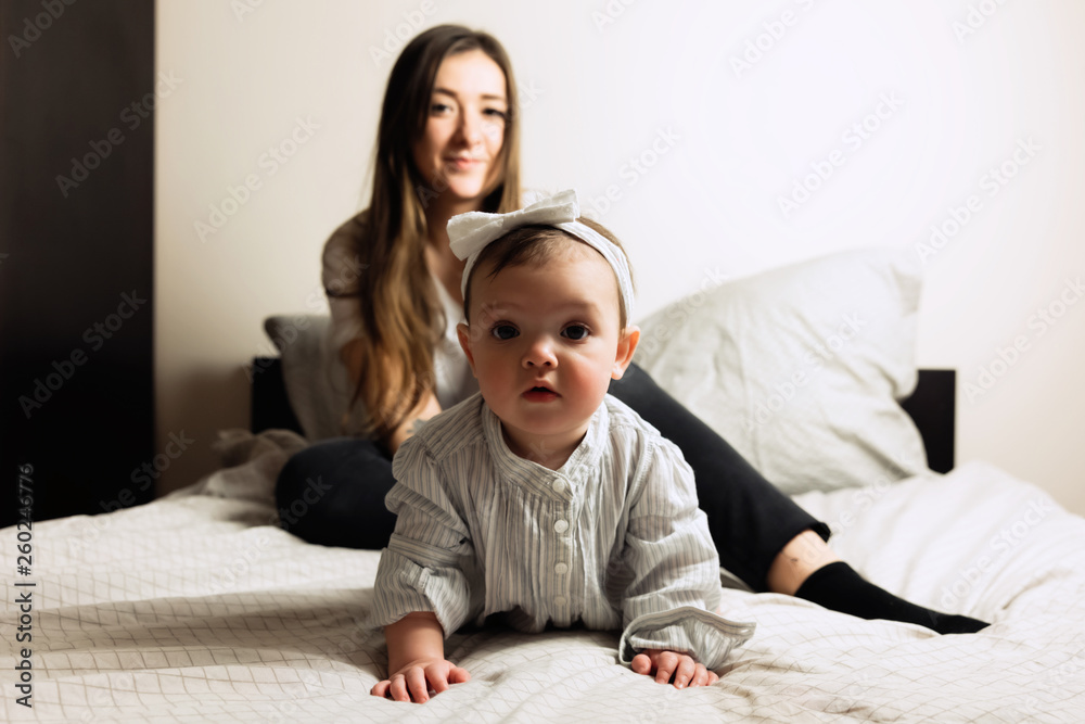 Young mother with a small daughter playing on the bed. Happy childhood. Young mother with a small daughter playing on the bed. Happy childhood.