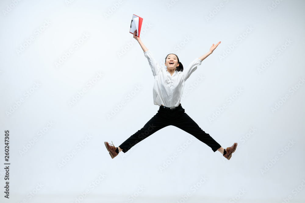 Reach new heights for your family. Happy woman working at office, jumping and dancing in casual clothes or suit isolated on white studio background. Business, start-up, working open-space concept.