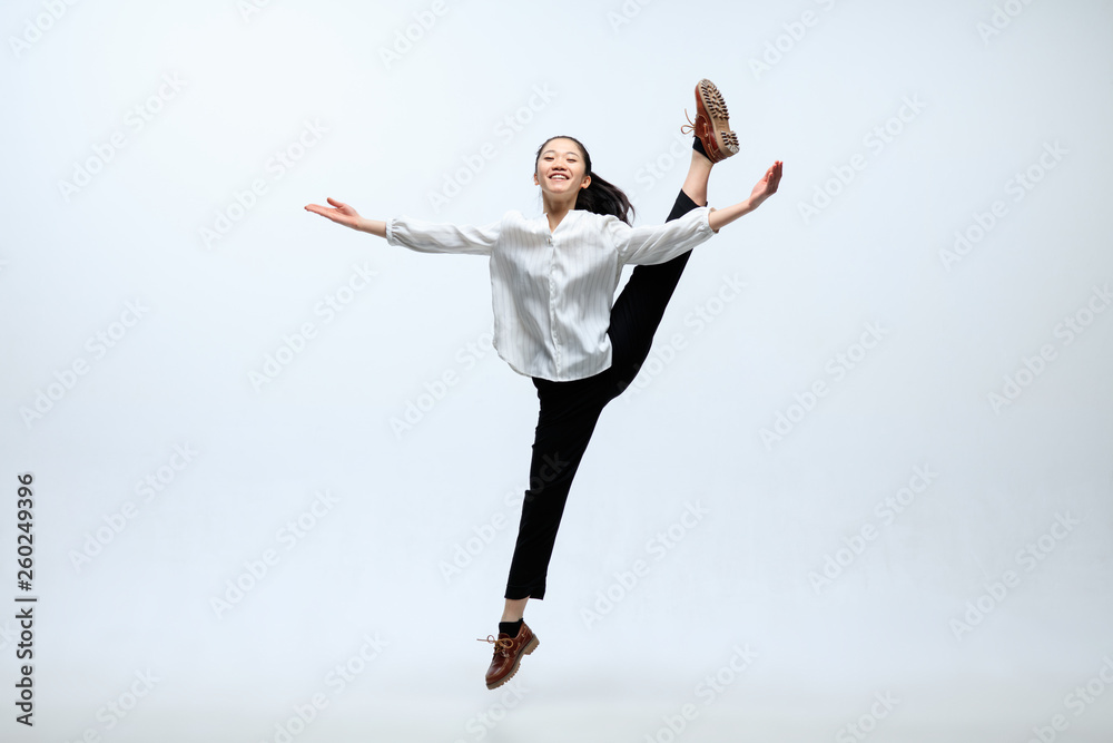 Obraz premium Winged flying by inspiration. Woman working at office, jumping and dancing in casual clothes or suit isolated on white studio background. Business, start-up, working open-space concept.