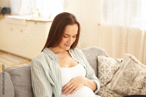Happiness  joy  youth and motherhood concept. Pregnant girl having amazed facial expression  looking down at her large belly  excited with quickening  feeling deep connection with her unborn baby