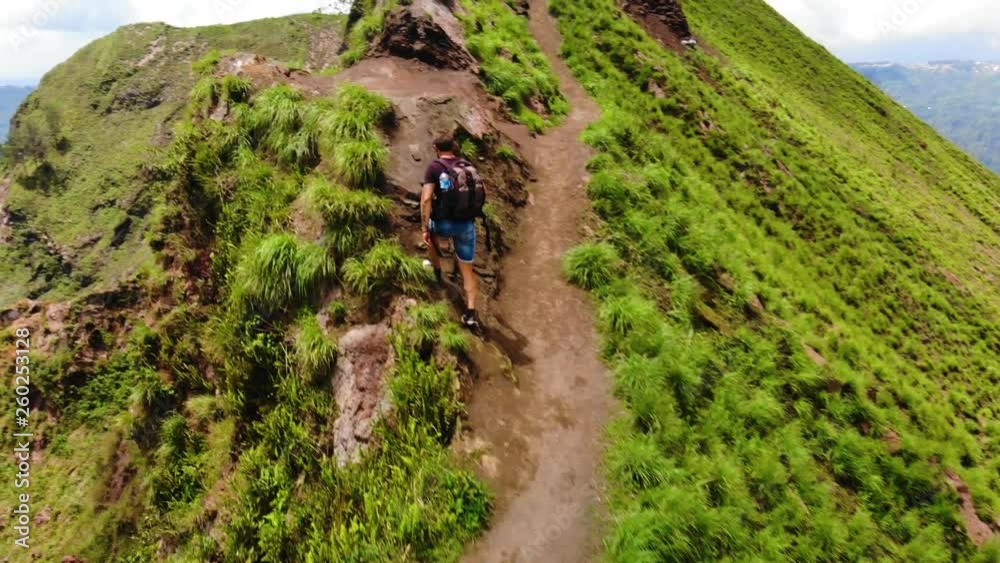 Drone following an European tourist wearing a backpack, walking to the top of an active vulcano Mount Batur in Bali, Indonesia. Drone following an European tourist wearing a backpack, walking to the top of an active vulcano Mount Batur in Bali, Indonesia.