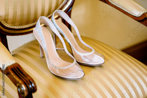 bridal shoes on a chair with a striped golden upholstery and wooden handles