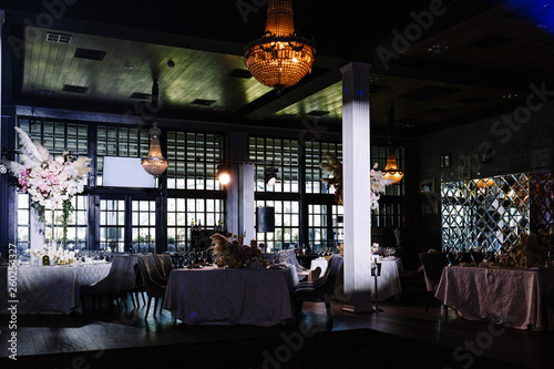 a wedding hall decorated with flowers and a chic chandelier hanging from the ceiling