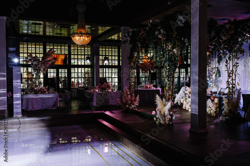 a wedding hall decorated with flowers and a chic chandelier hanging from the ceiling