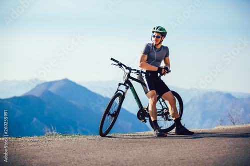 Fototapeta Naklejka Na Ścianę i Meble - Athletic sportsman cyclist standing with bike enjoying beautiful view.