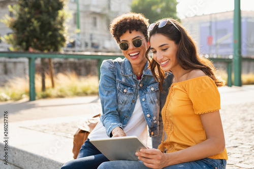 Two women using digital tablet outdoor photo