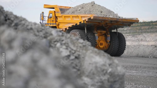 Truck driving career on road. Dump truck carries ore mined in open pit. Heavy large transport in mining industry on background of open white multistage quarry photo