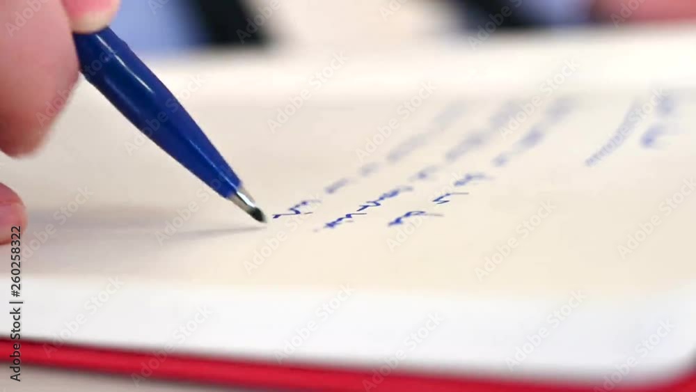 Mann schreibt mit blauem Stift in Notizbuch