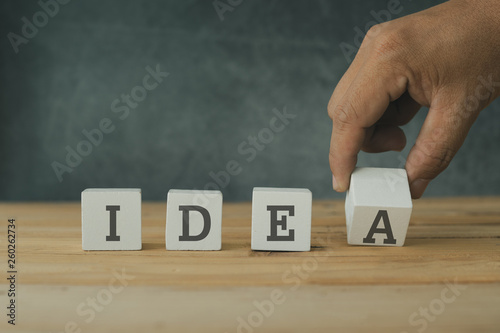 Creative and success concept, hand  putting wood cube block with word idea on wooden table.