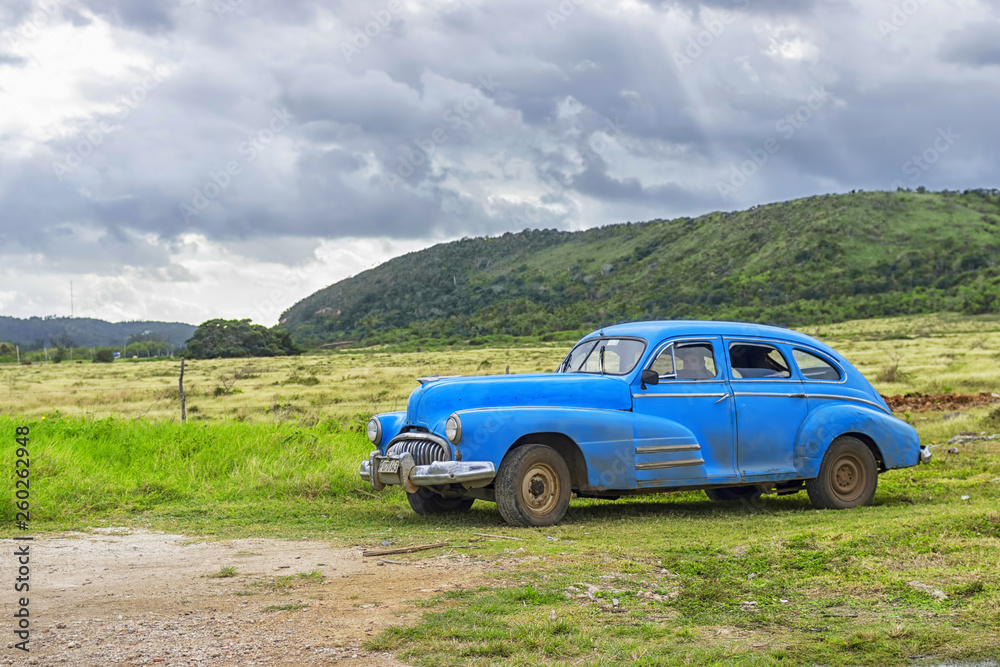 HAVANA, CUBA - JANUARY 04, 2018: A retro classic American car parked against the backdrop of mountains and overcast sky in Cuba