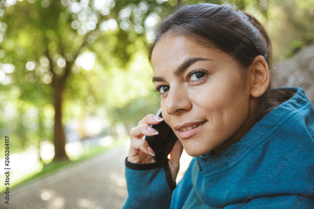 Smiling sportswoman talking on mobile phone