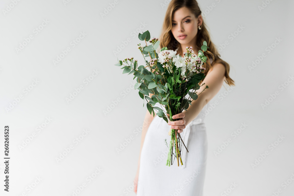 selective focus of flowers in hand of attractive girl on white selective focus of flowers in hand of attractive girl on white