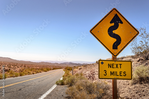 Desert road with winding road sign.