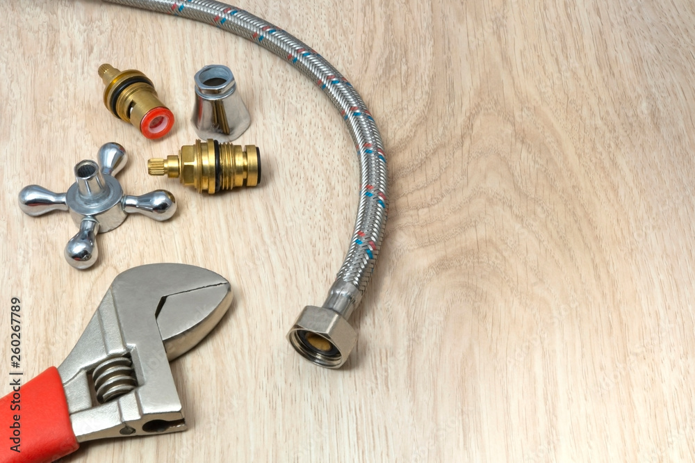 Plumbing tools and replacement parts on a wooden table. Plumbing tools and replacement parts on a wooden table.