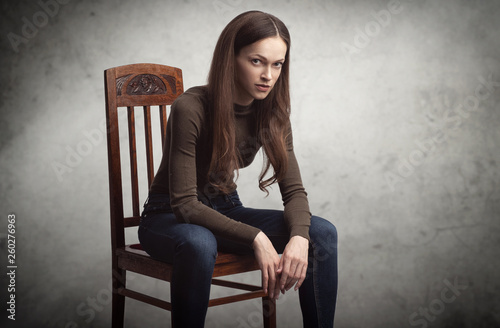 pretty brunette woman is sitting on a chair in studio photo