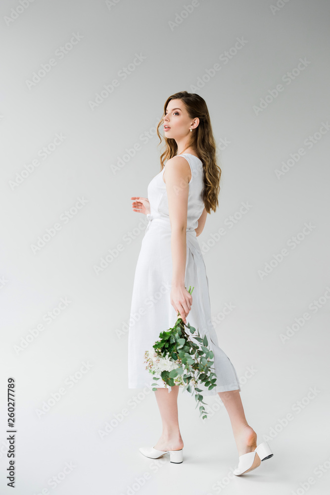attractive girl in dress walking with flowers on grey attractive girl in dress walking with flowers on grey