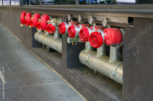 Bright red hydrant booster valves with metal pipes and red caps