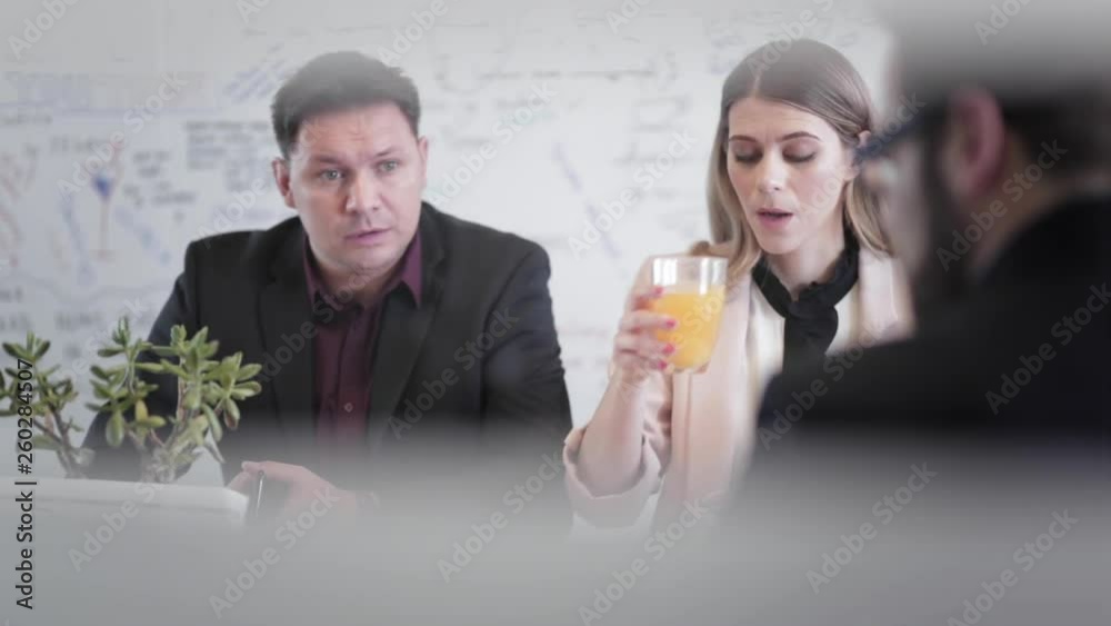Static shot of a group of business coworkers sitting by the office desk, discussing ideas during a meeting in the conference room.
