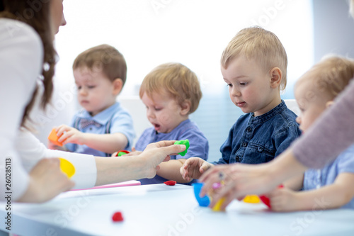 Children with teacher play colorful clay toy