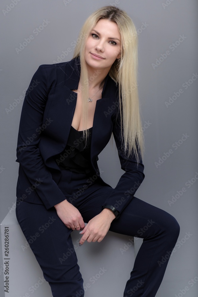 Portrait of happy smiling young cheerful businesswoman sitting. Success in business concept studio shot talking to a client. Gray suit. Portrait of happy smiling young cheerful businesswoman sitting. Success in business concept studio shot talking to a client. Gray suit.