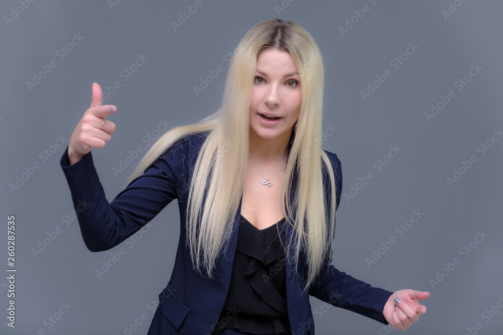 Portrait of happy smiling young cheerful businesswoman standing. Success in business concept studio shot talking to a client. Gray suit. Portrait of happy smiling young cheerful businesswoman standing. Success in business concept studio shot talking to a client. Gray suit.