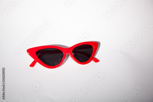 Red sun glasses resting on grey and clean background with dark lens