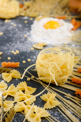 preparing pasta  eggs  flour  various types of pasta  spaghetti  on dark background.from above.