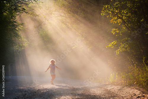 Young woman in the sun on a forest road.