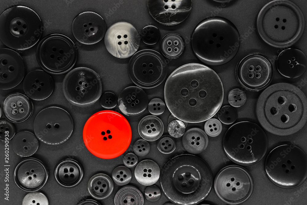 Various dark clothes buttons background with one red button Various dark clothes buttons background with one red button