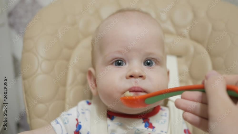 A six-month-old baby boy first tries baby food. Healthy nutrition for children. A six-month-old baby boy first tries baby food. Healthy nutrition for children.