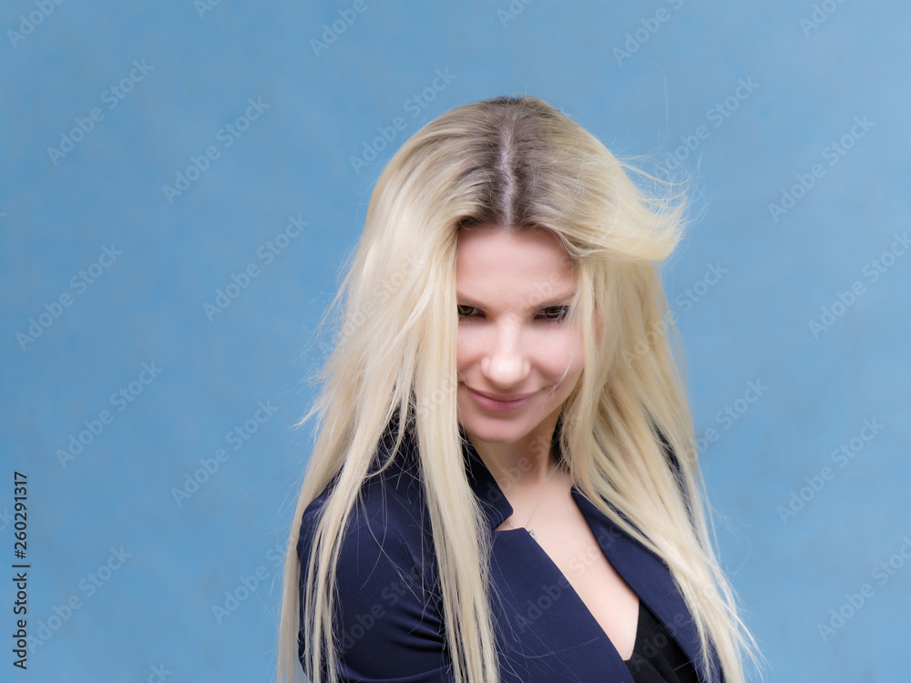 Portrait of happy smiling young cheerful businesswoman standing with flowing hair. Success in business concept studio shot. Blue suit.